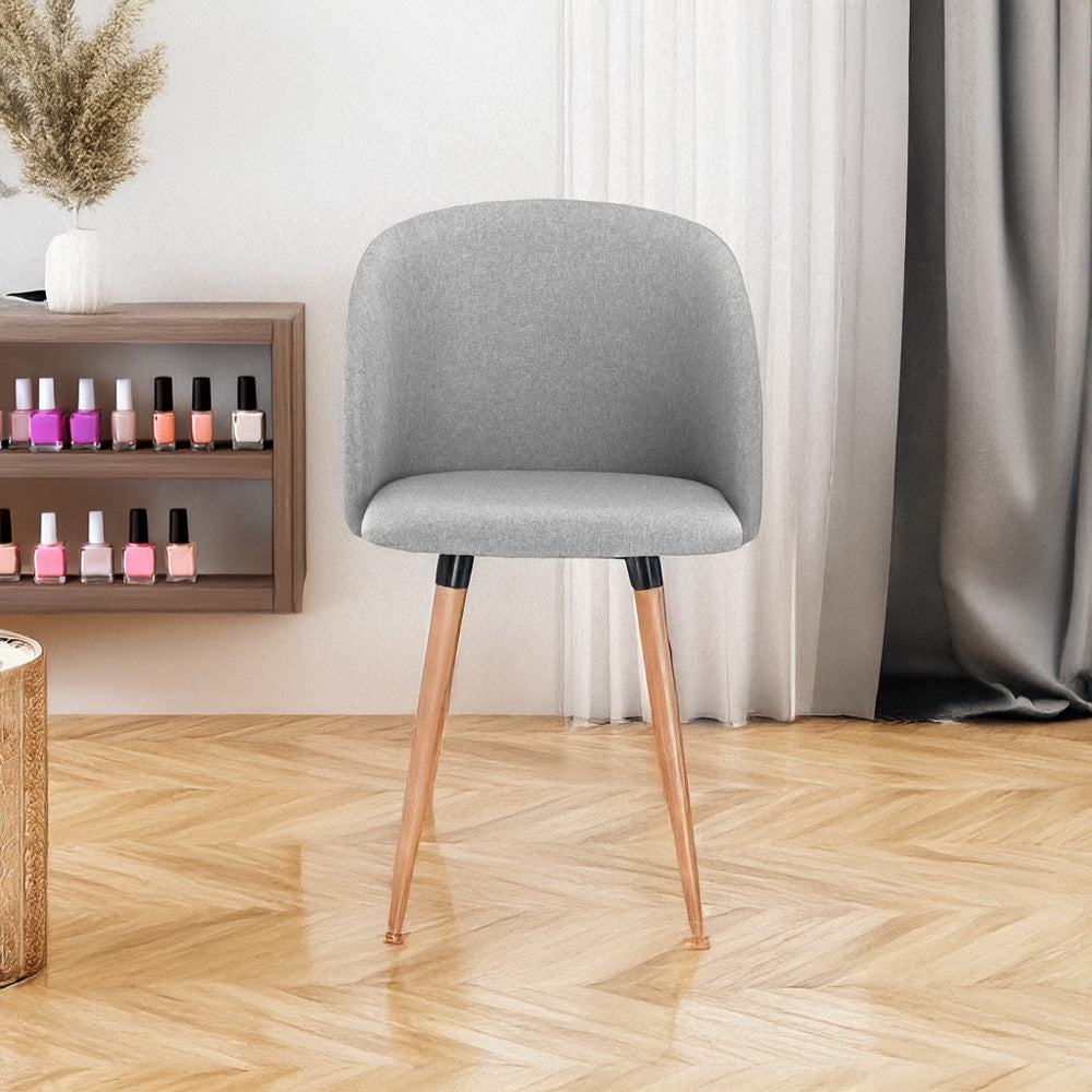 Chaise manucure scandinave gris clair dans un salon esthétique, devant une étagère avec vernis à ongles.