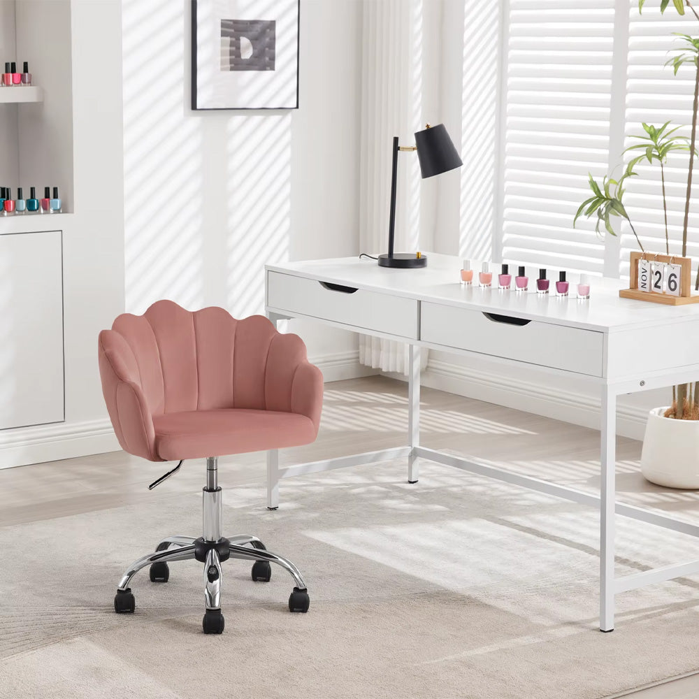 Chaise prothésiste ongulaire en velours rose installée devant un bureau blanc avec des vernis à ongles exposés.