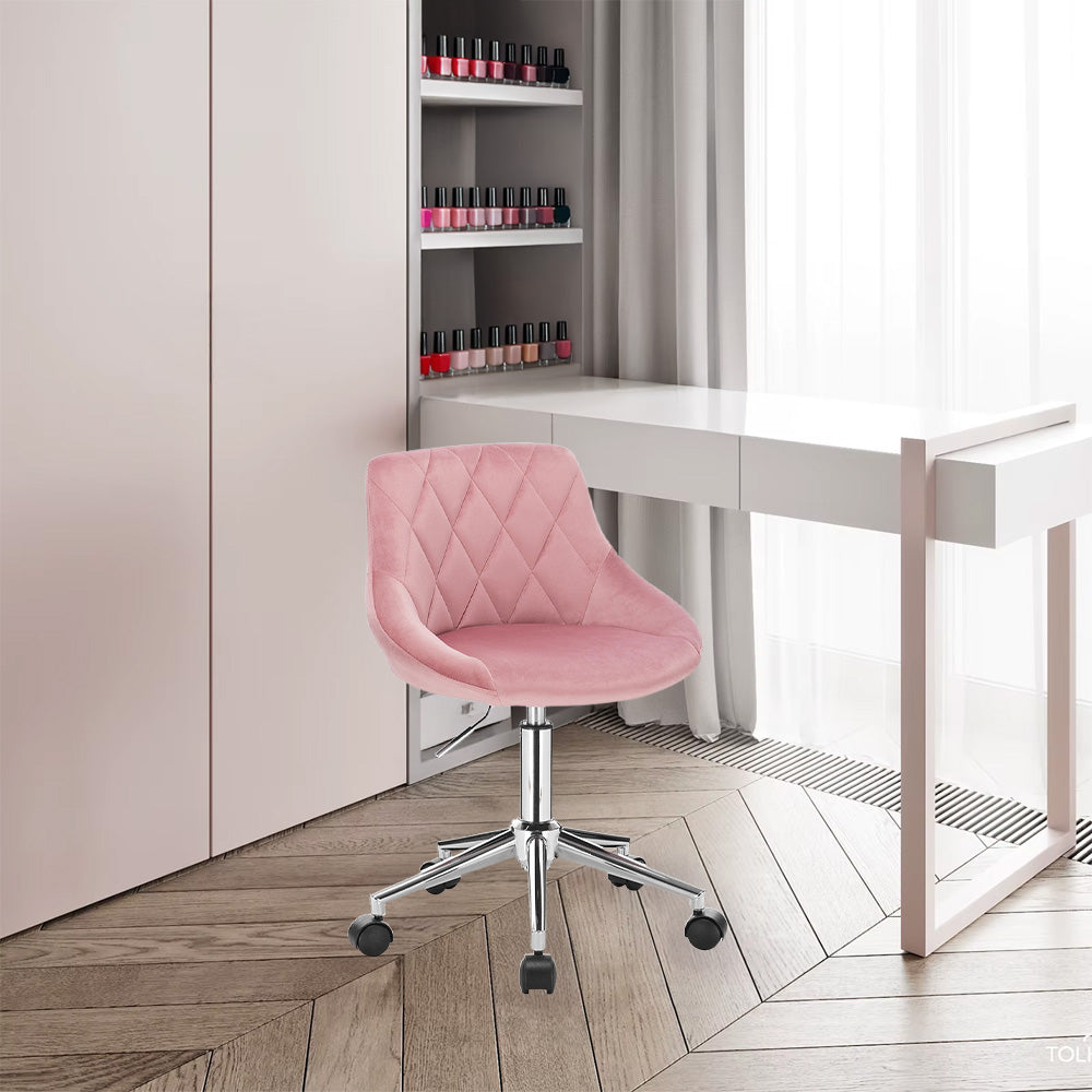 Chaise en velours rose placée devant une table de manucure blanche, dans un salon professionnel élégant.
