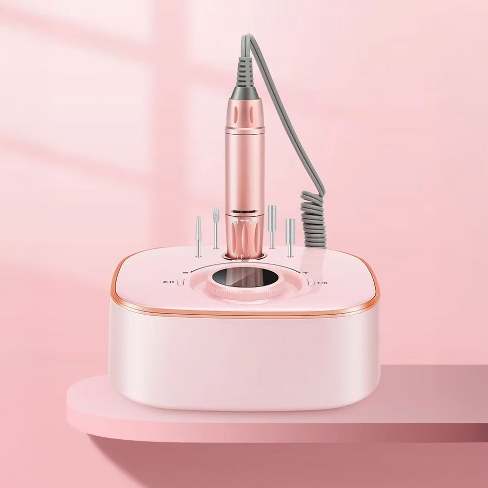 Mise en scène de la ponceuse à ongles électrique posée sur un support rose, avec rangement pour embouts et espace pour la pièce à main.