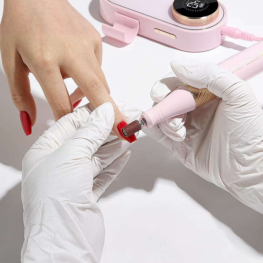 Manucure en cours avec la ponceuse à ongles 40000 RPM, un professionnel portant des gants effectue un soin de précision sur des ongles rouges.