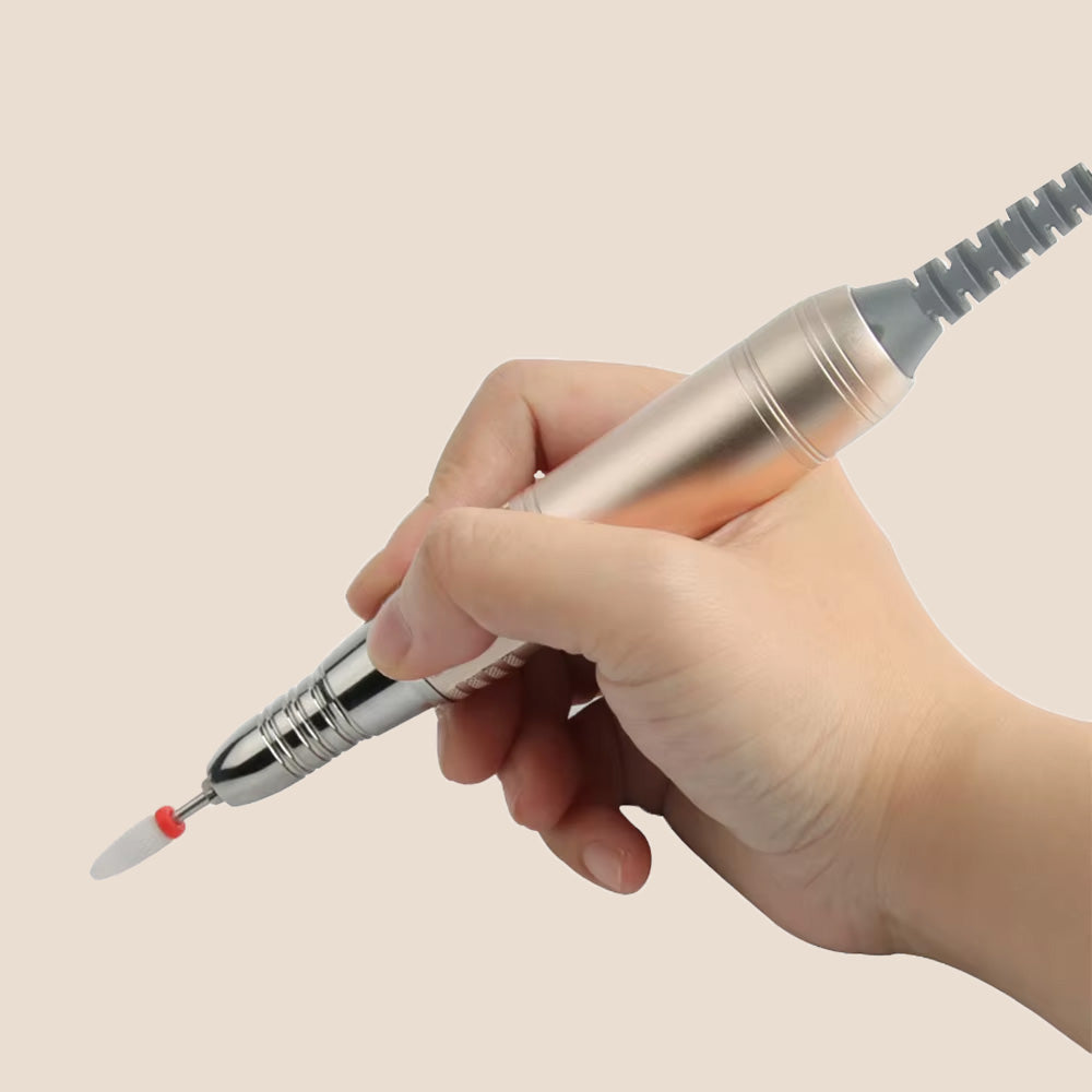 Gros plan sur une main tenant le stylo ponceuse doré, mettant en avant la prise en main ergonomique et l'embout de limage.