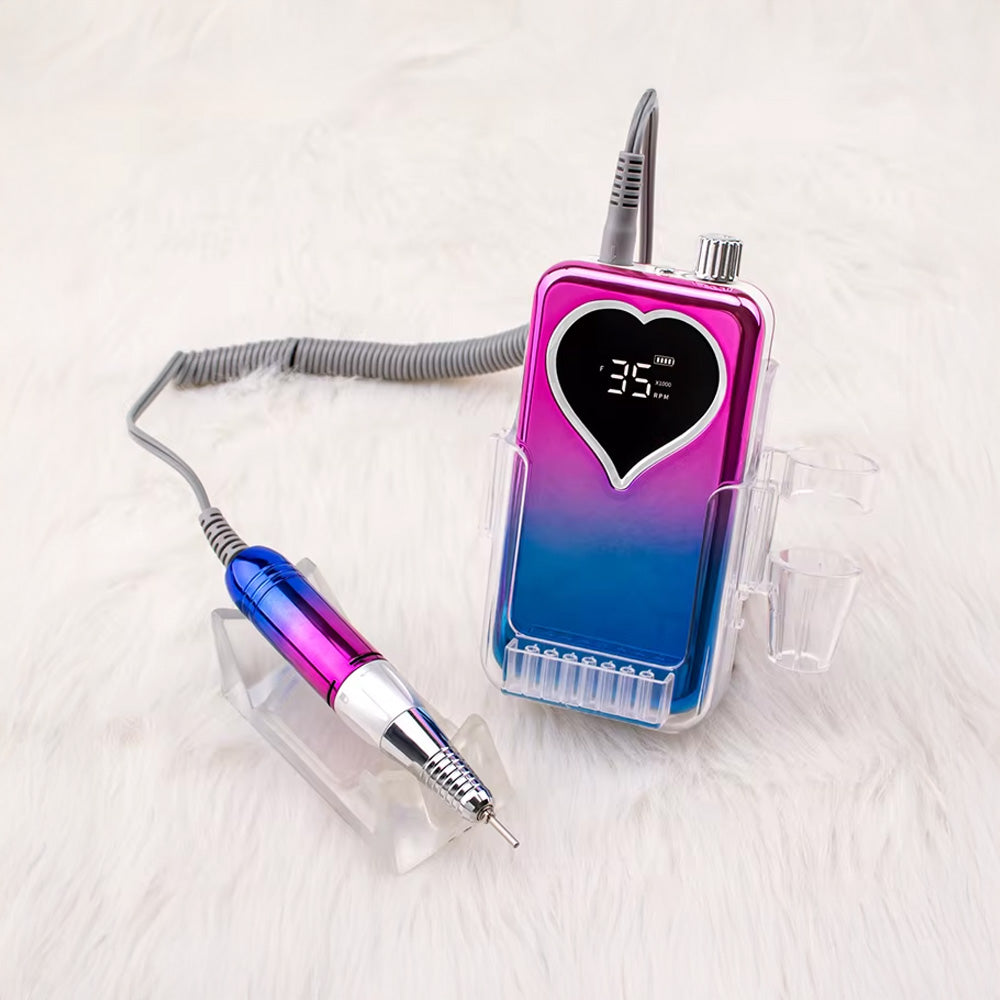 Ponceuse à ongles rose et bleue posée sur un support transparent, avec sa pièce à main assortie prête à l'emploi.
