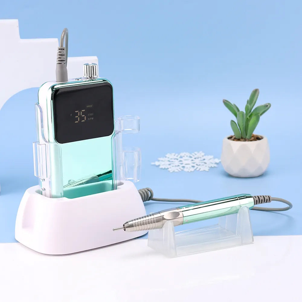 Vue latérale de la ponceuse à ongles vert métallisé avec sa pièce à main posée sur un support transparent, mettant en avant son design moderne et sa finition brillante.