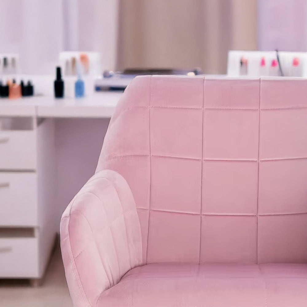 Gros plan sur l’accoudoir et le dossier matelassé de la chaise manucure rose, ambiance institut de beauté.