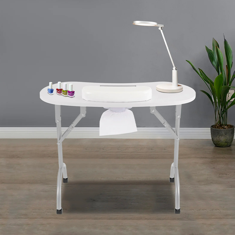 Table manucure pliable avec un aspirateur vu de face, modèle blanc dans un institut de beauté avec une jolie plante en fond